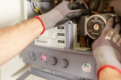 Technicien intervenant sur une chaudière ancienne, type d'équipement courant dans les passoires thermiques classées F ou G