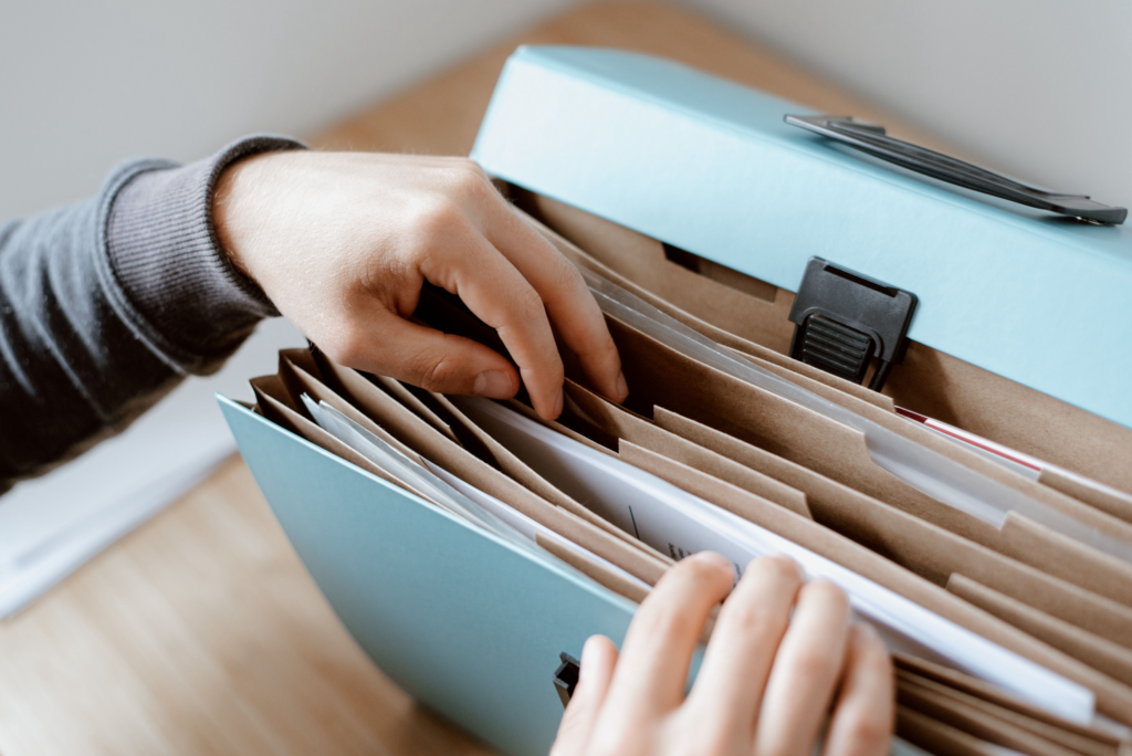 Main feuilletant des dossiers ; dossier 'diagnostic termites' dans une boîte de classement