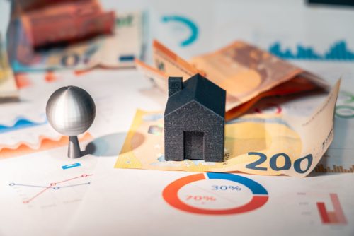 Maquette de maison posée sur des billets de 200 euros et des graphiques illustrant le coût d'un DPE en 2026